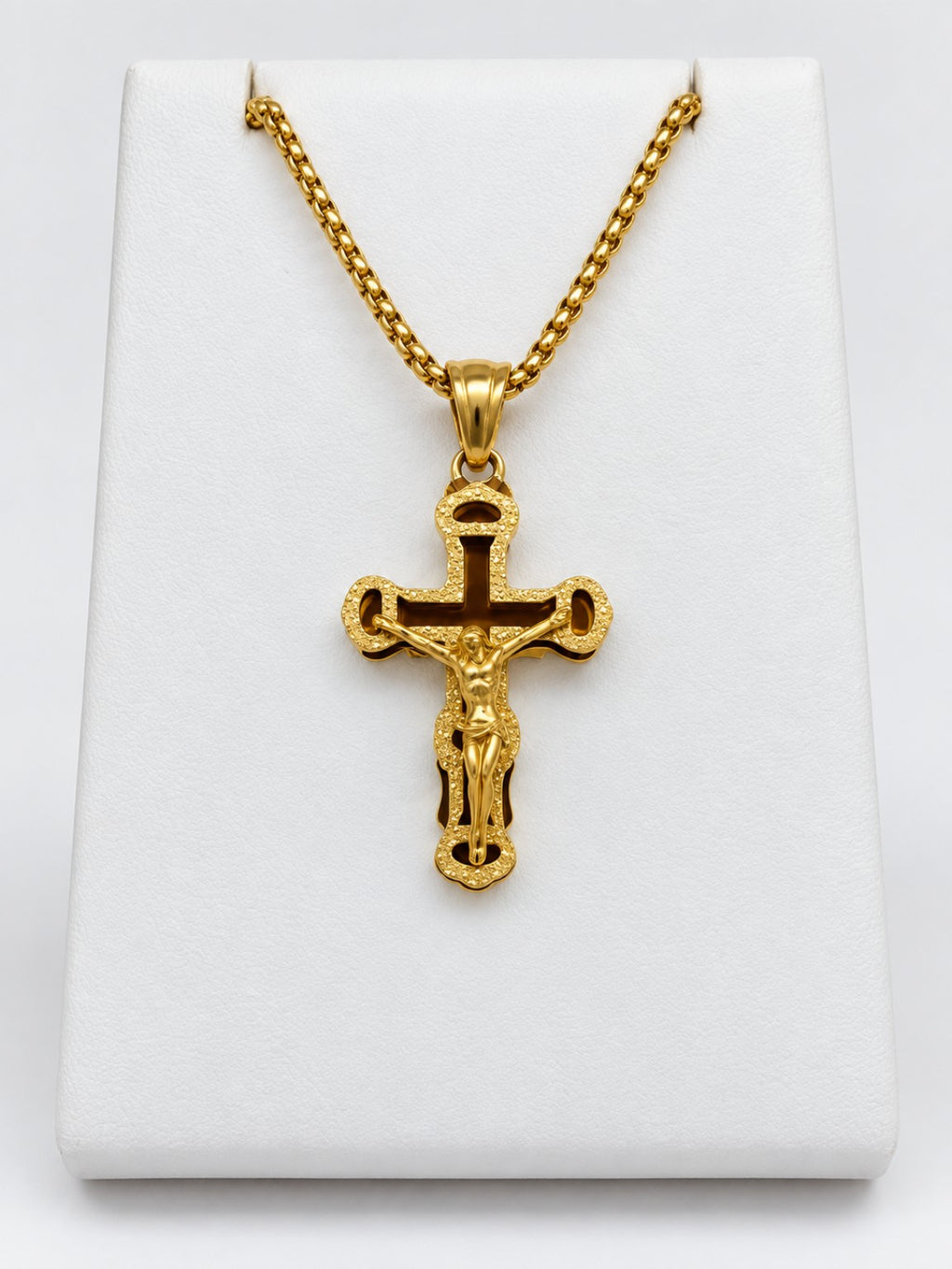 An ornate gold-tone crucifix with a textured decorative border, open details and a raised figure of Jesus.