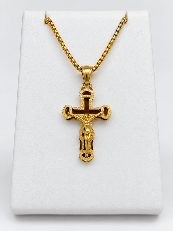 An ornate gold-tone crucifix with a textured decorative border, open details and a raised figure of Jesus.