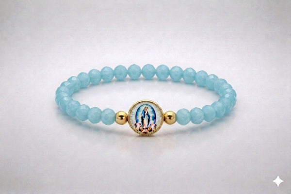 Our Lady of Grace light blue crystal elastic bracelet with gold-tone centerpiece, front view
