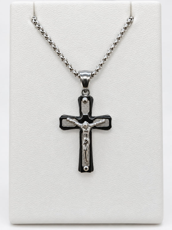 A crucifix with silver-tone textured panels, a dark border, a raised silver-tone figure of Jesus and silver-tone chain.