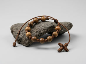 Brown wood bead knotted decenario rosary bracelet on a stone display