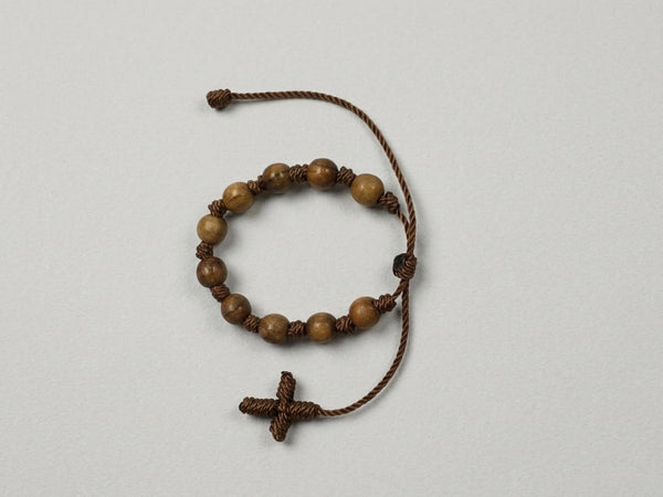 Wooden bead adjustable decade rosary bracelet with brown cord cross on light background