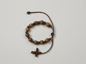 Wooden bead adjustable decade rosary bracelet with brown cord cross on light background